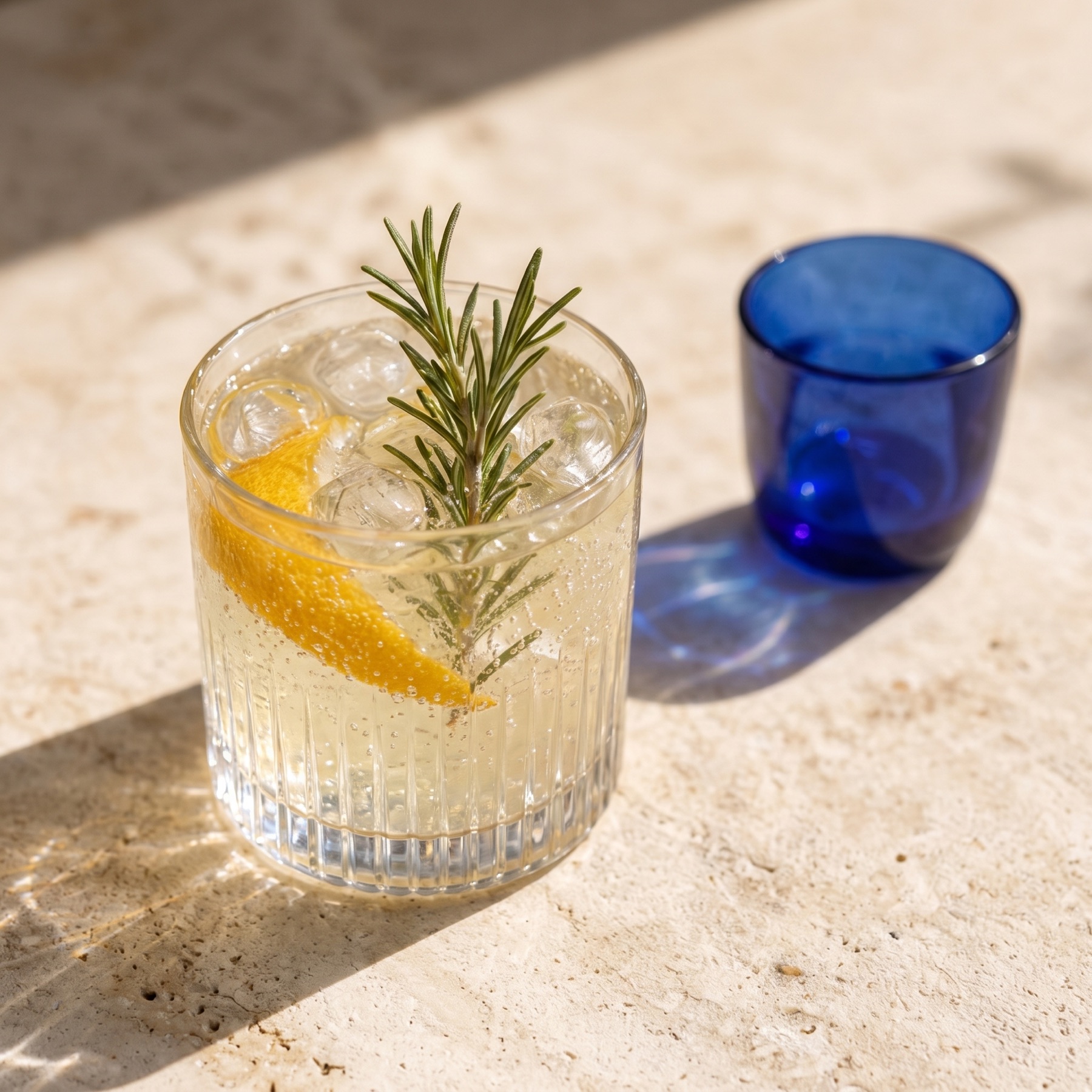 Rosemary tonic with lemon and ice beside a cobalt glass